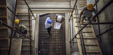 Construction workers and architects at a construction site viewed from above.